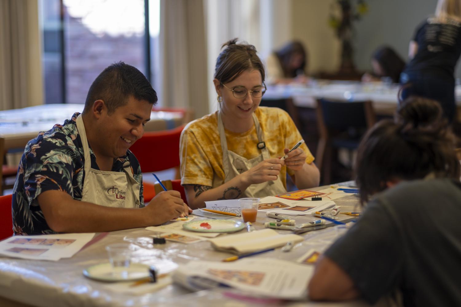Two students laugh while painting in Norlin Library
