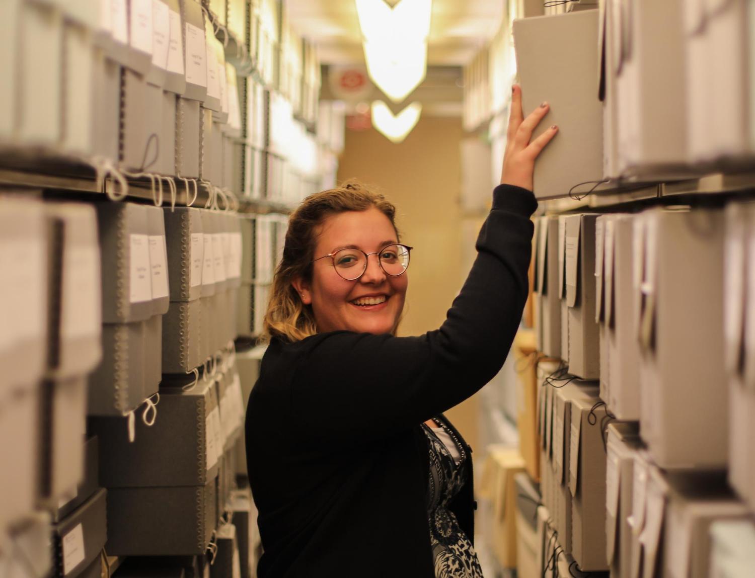 Archivist Ashlyn Velte pulling a box from a shelf in the Archives. 