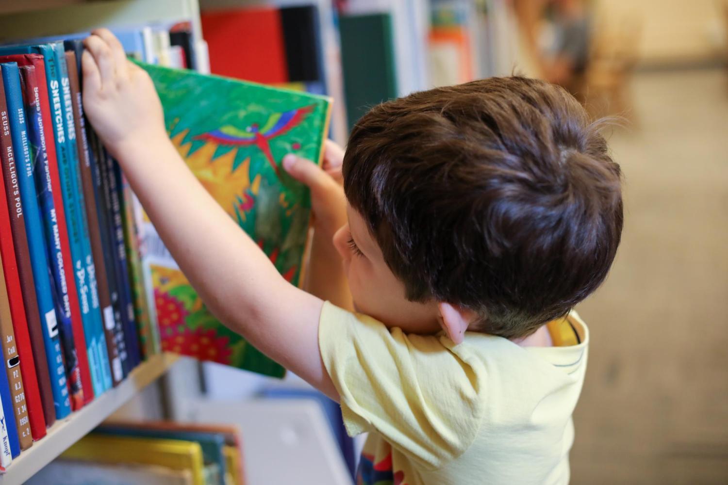 Young child removes a book from the Children's and Young Adult Collection at Norlin Library.