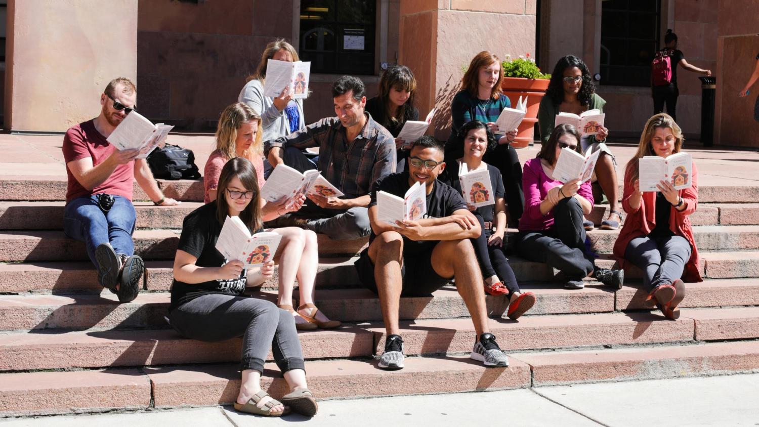 A group sits on the steps of Norlin reading Sabrina & Corina