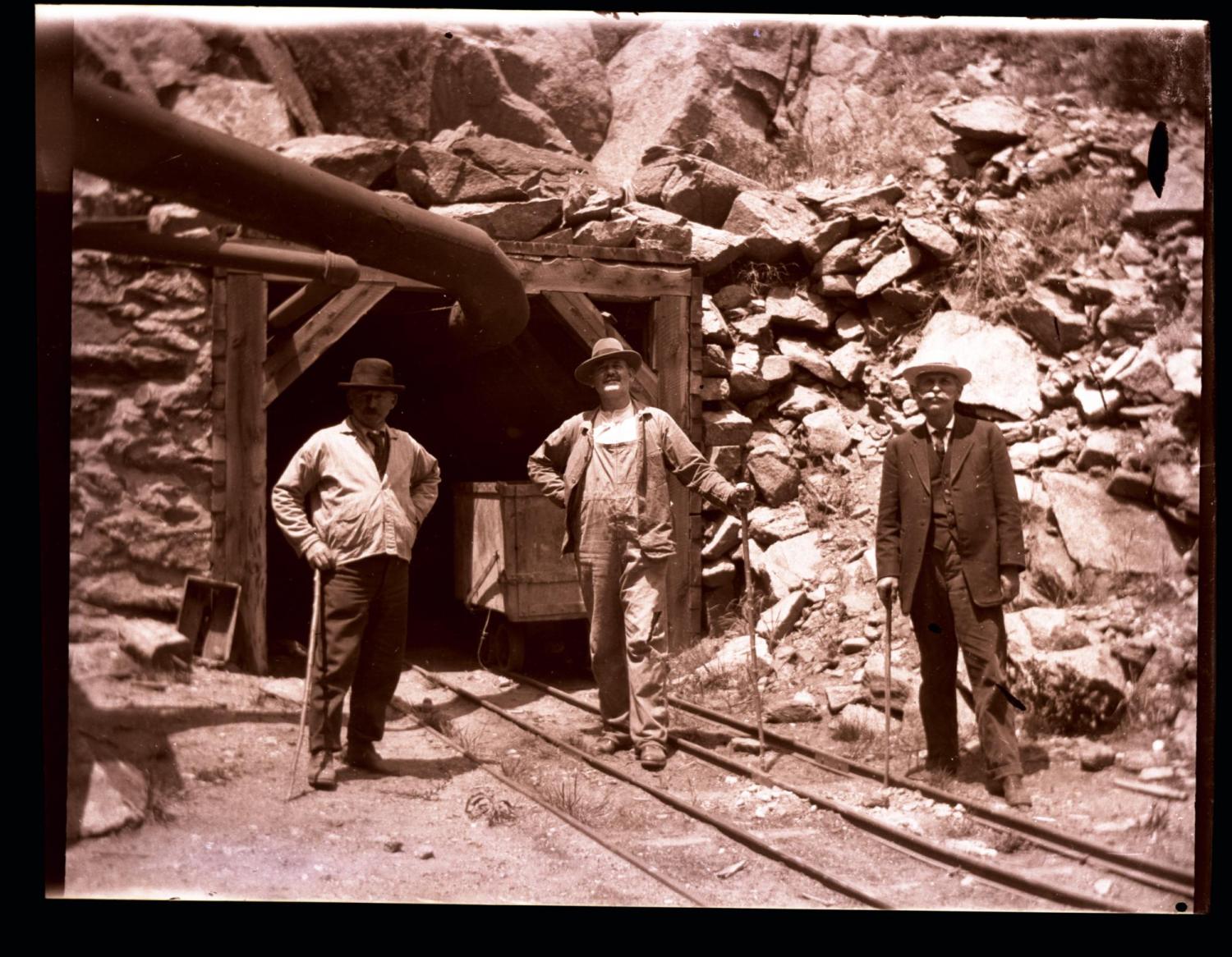 Three men standing outside a mine shaft, unknown date