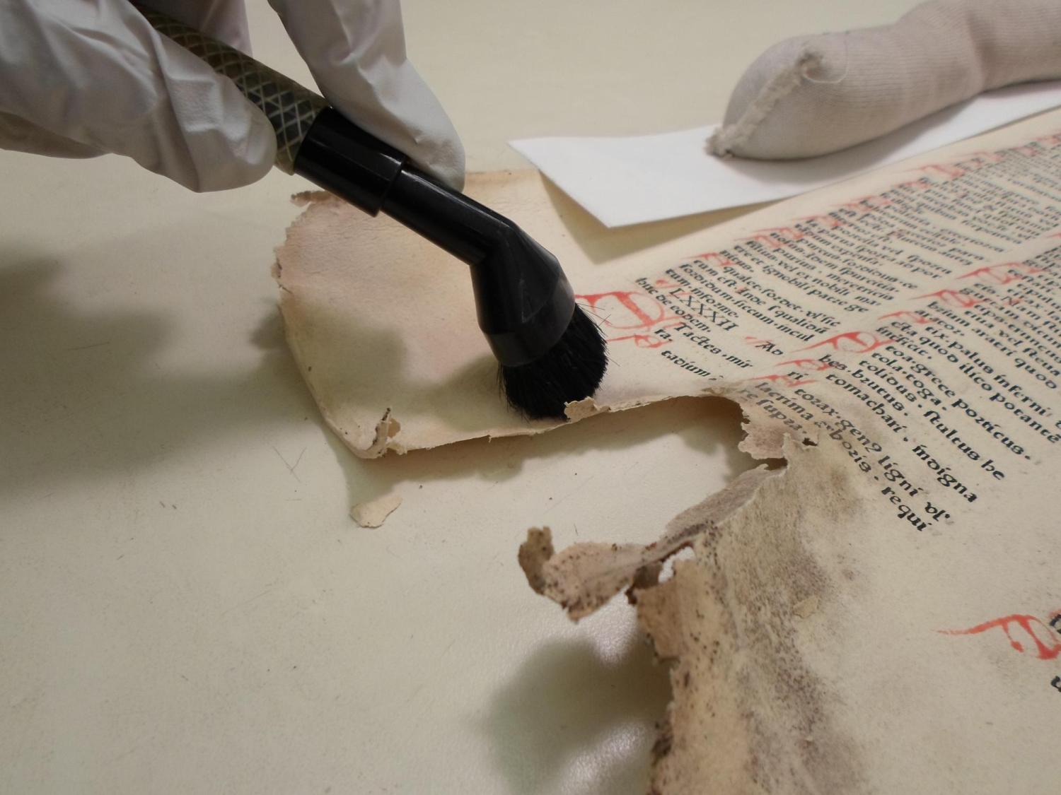 A preservationist works on cleaning an old and damaged document.