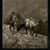 Man and a burro loaded with bags on the mountain side. Details unknown.